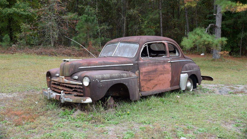 rusty Ford coupe in field